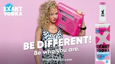 Boca vrhunske votke u prvom planu ispred žene s ružičastim boomboxom.