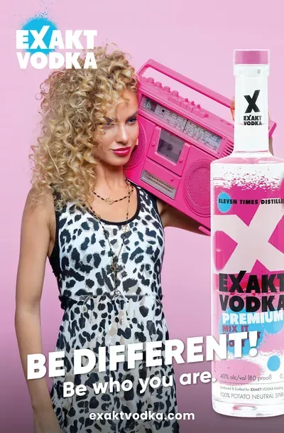 U prvom planu je boca vrhunske votke, dok u pozadini žena drži ružičasti boombox.